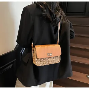 Detail of handwoven straw crossbody bag with brown leather flap and golden metal clasp