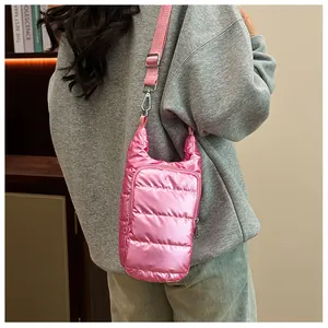 Pink quilted down shoulder bag with adjustable strap worn on grey sweatshirt