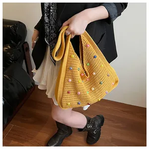Close-up of yellow knit tote bag featuring colorful faux pearl beads and shoulder strap