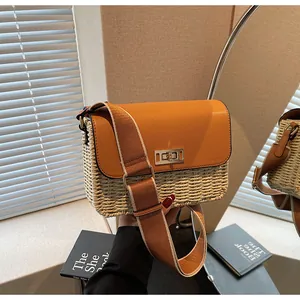 Detail of woven straw and orange leather crossbody bag with golden square lock
