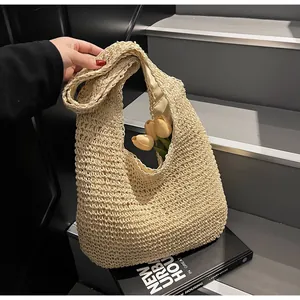 Straw woven tote bag with light lining on grey stairs with flowers and books