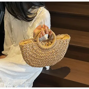 Détail d'un sac en paille avec anses rondes et doublure en tissu à fermeture par cordon