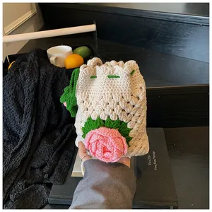 Makro-Detail einer handgehäkelten Kordeltasche mit rosa 3D-Häkelrose und grünem Blattdekor