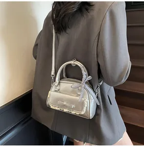 Detail of silver metallic handbag with lace bow pocket and checkered ribbon handle