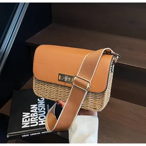Detail of woven straw handbag featuring a brown leather flap and golden metal swivel lock