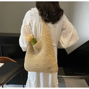 Grande borsa tote in paglia fatta a mano portata da una modella in abito di pizzo bianco