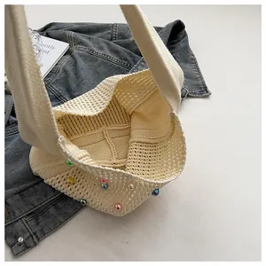Detailed close-up of cream knit tote bag featuring colorful bead accents and woven texture