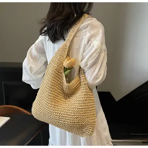 Dettaglio della borsa in paglia con tulipani che mostra trama a rete e tracolla