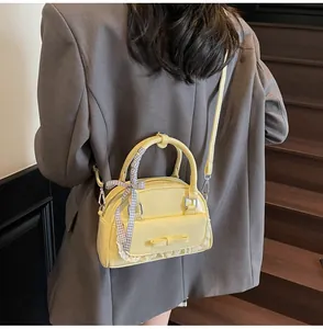 Detail of yellow bow shoulder bag with white lace trim and checkered ribbon on the strap