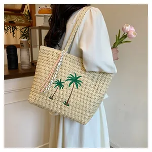 Close-up of palm tree embroidery and woven texture on large straw tote bag