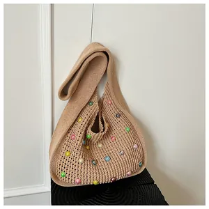 Close-up of beige knit shoulder bag with colorful pearls and soft crochet texture