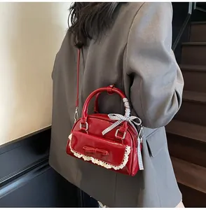 Detail of red patent leather bowling bag with lace pocket and ribbon-wrapped handle