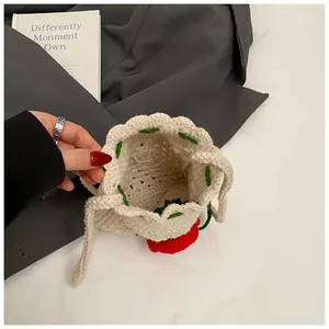 Detail der handgehäkelten Kordeltasche mit roten floralen Akzenten und Strickstruktur
