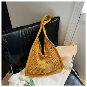 Detail of a yellow knitted tote bag with colorful beads on a black leather chair