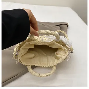 Dettaglio borsa in paglia intrecciata con fiocco in pizzo e fodera con coulisse