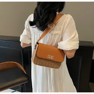 Detail of straw crossbody bag with brown leather strap and gold metal twist lock closure
