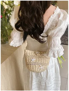 Détail du sac en paille avec étoiles de mer coquillages et robe en dentelle de plage