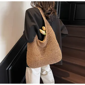 Dettaglio di borsa hobo in paglia intrecciata con fiori su scale minimaliste