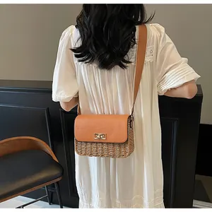 Detail of straw crossbody bag with orange leather flap and gold twist-lock on a model