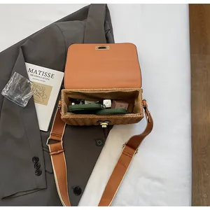 Interior detail of a rectangular straw crossbody bag with leather lining and canvas strap