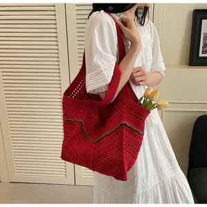 Close-up of red crochet tote bag with green wavy trim and knit texture on white dress