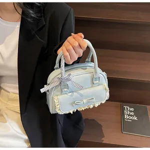 Detail of light blue bow handbag with lace trim and checkered ribbon on the handle