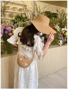 Détail du mini sac bandoulière en paille avec étoile de mer et robe en dentelle de plage