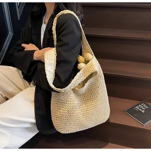 Dettaglio di una grande borsa tote in paglia beige con trama intrecciata in legno