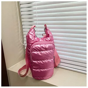 Detailed shot of a pink quilted down crossbody bag with a metallic satin finish and strap