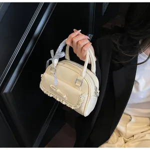 Detail of creamy white bowling bag with lace trim, bow, and blue checkered ribbon handle