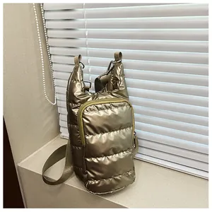 Close-up of metallic bronze quilted down bag with adjustable khaki shoulder strap on window sill