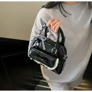 Detail of glossy black patent leather bowling bag with bow and lace trim decoration