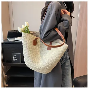 Close-up of beige straw tote bag with brown leather handles and woven texture details