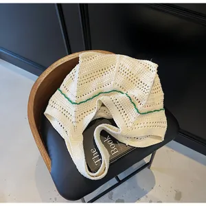 Detail view of cream crochet knit tote bag with green stripe on a designer chair