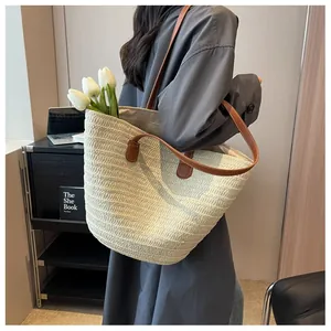 Détail du sac cabas tissé avec des lanières en cuir marron porté à l'épaule