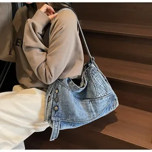 Detail view of washed denim tote bag showing metal buttons and stitching on wide shoulder strap
