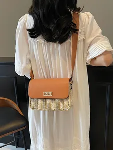 Fashionable straw crossbody bag with brown leather flap on a white lace dress