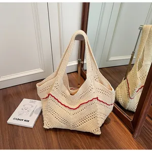Detailed macro view of the cream-white knit tote with decorative red wavy embroidery