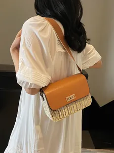 Straw weave shoulder bag with tan leather flap and metallic lock worn with a white dress