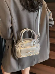 Silver metallic bow handbag with lace trim and checkered scarf handle shown as crossbody