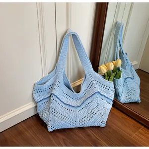 Close-up of light blue crochet knit tote bag with V-shaped wave pattern and floral decor