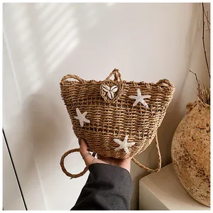 Détail d'un sac en paille fait main avec étoiles de mer et coquillages sur la bandoulière
