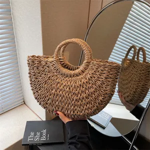 Vue détaillée de la texture tressée du sac à main en paille beige avec anses rondes