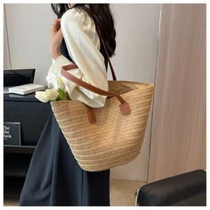 Détail d'un sac cabas en paille tissée avec anses en cuir marron et finitions de couture