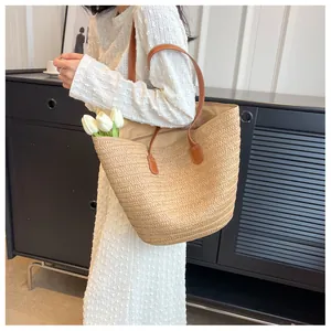 Détail du sac cabas en paille tressée avec anses en cuir brun et surpiqûres