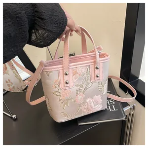 Detail of pink floral embroidery on satin fabric with silver metal studs on the bucket bag