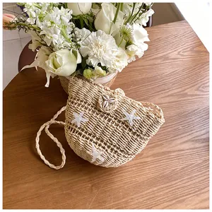 Détail d'un sac en paille tressée avec étoiles de mer et coquillages sur table bois