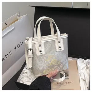 Detail of elegant floral embroidery on a white crossbody bag with silver rivet hardware