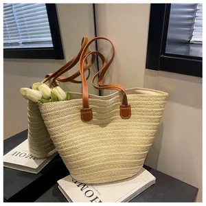Gros plan détaillé d'un grand sac cabas tissé beige avec des anses en cuir marron