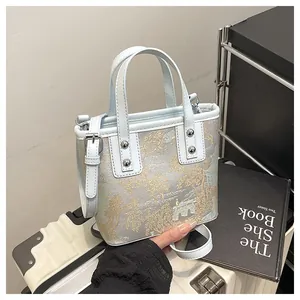 Detail of light blue jacquard bucket bag with landscape embroidery and silver rivets